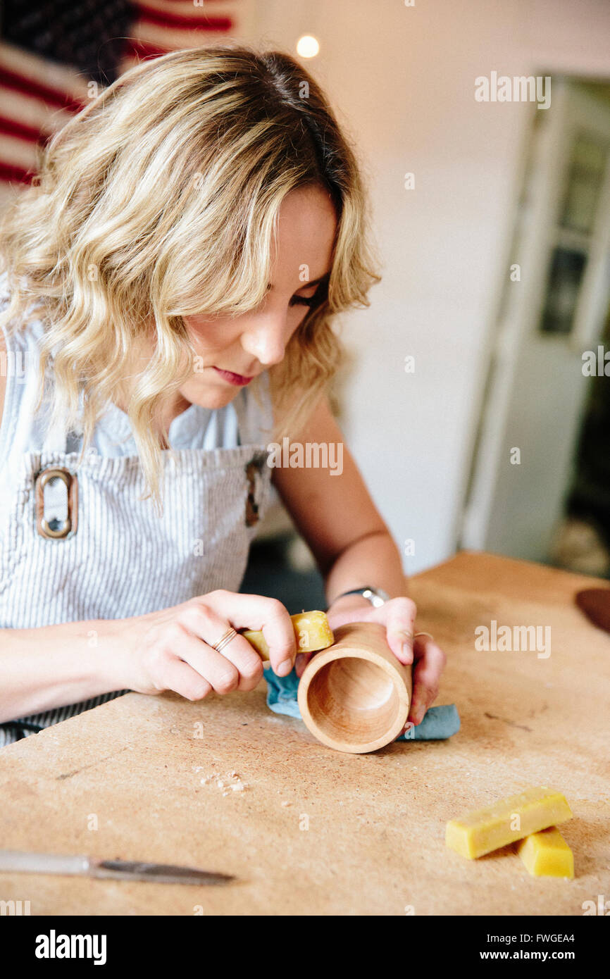 Una mujer en un taller con una losa de cera al aceite un pequeño bosque convertido taza o tazón. Foto de stock