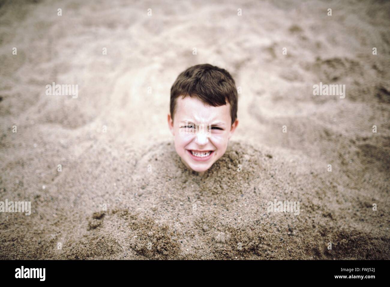 Un alto ángulo de visualización de Boy enterrado en la arena Foto de stock