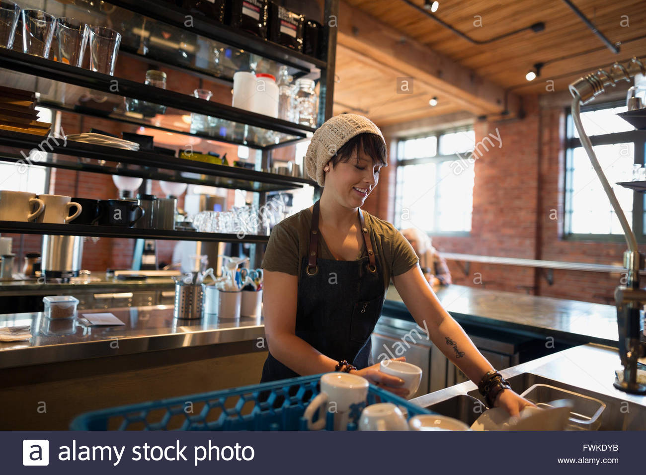 Trabajador lavar los platos en la cafetería. Foto de stock