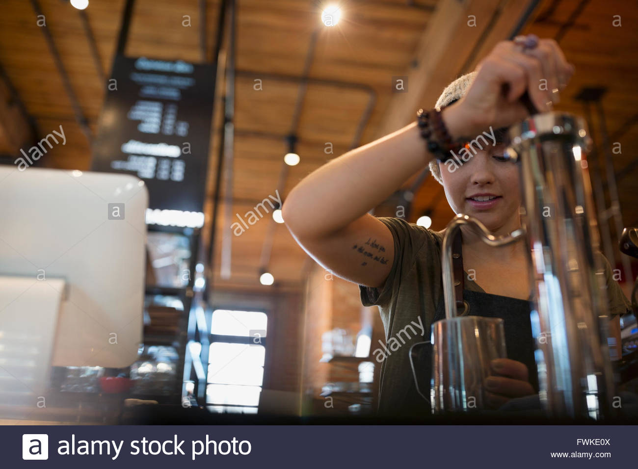 Barista espuma de leche en la cafetería. Foto de stock