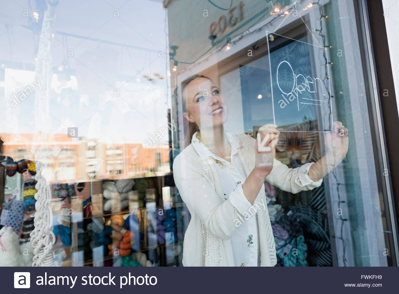 Dueño de la tienda sonriente volviendo abrir signo en la ventana Foto de stock
