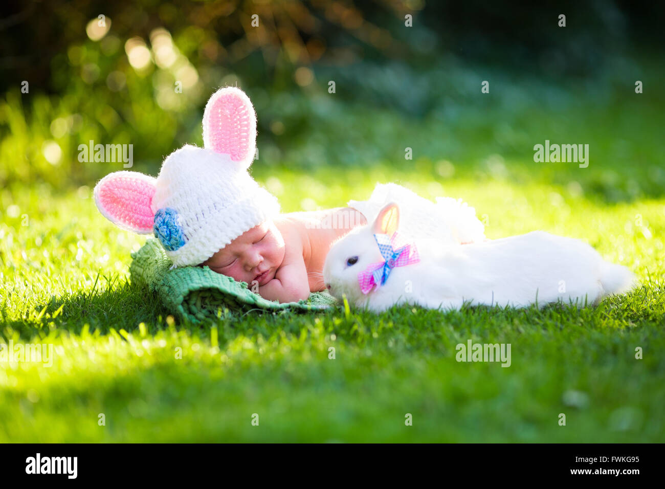 Lindo bebé recién nacido niño en traje de llevar sombrero con orejas y pañales blancos y un conejo real en el soleado jardín verde Fotografía de stock - Alamy