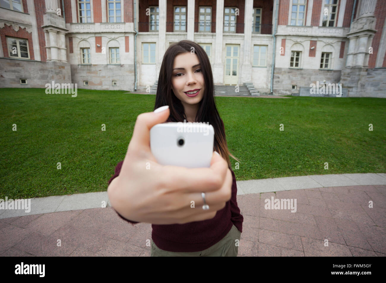 Viajar blanco joven selfie niña toma una foto con la cámara de su teléfono inteligente con algún viejo edificio en el fondo. Foto de stock