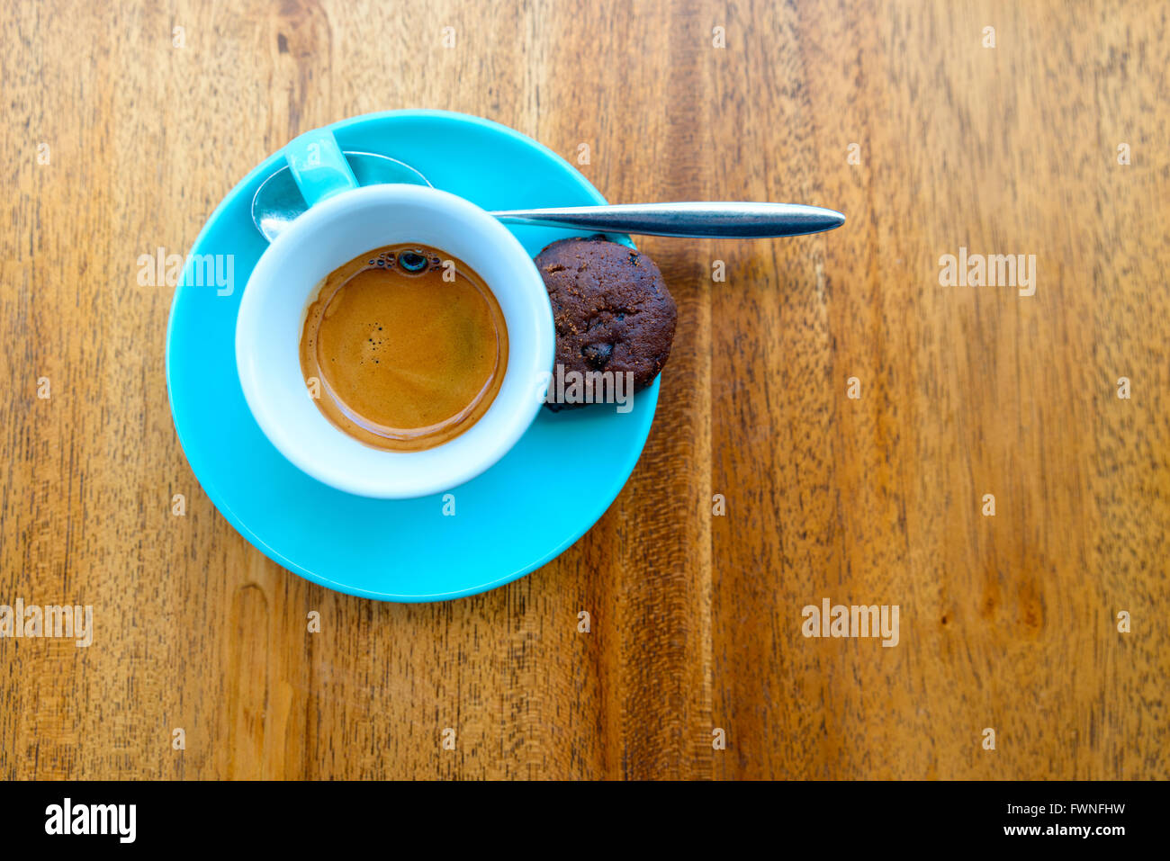 Un espresso en una taza turquesa sobre una tabla de madera Foto de stock