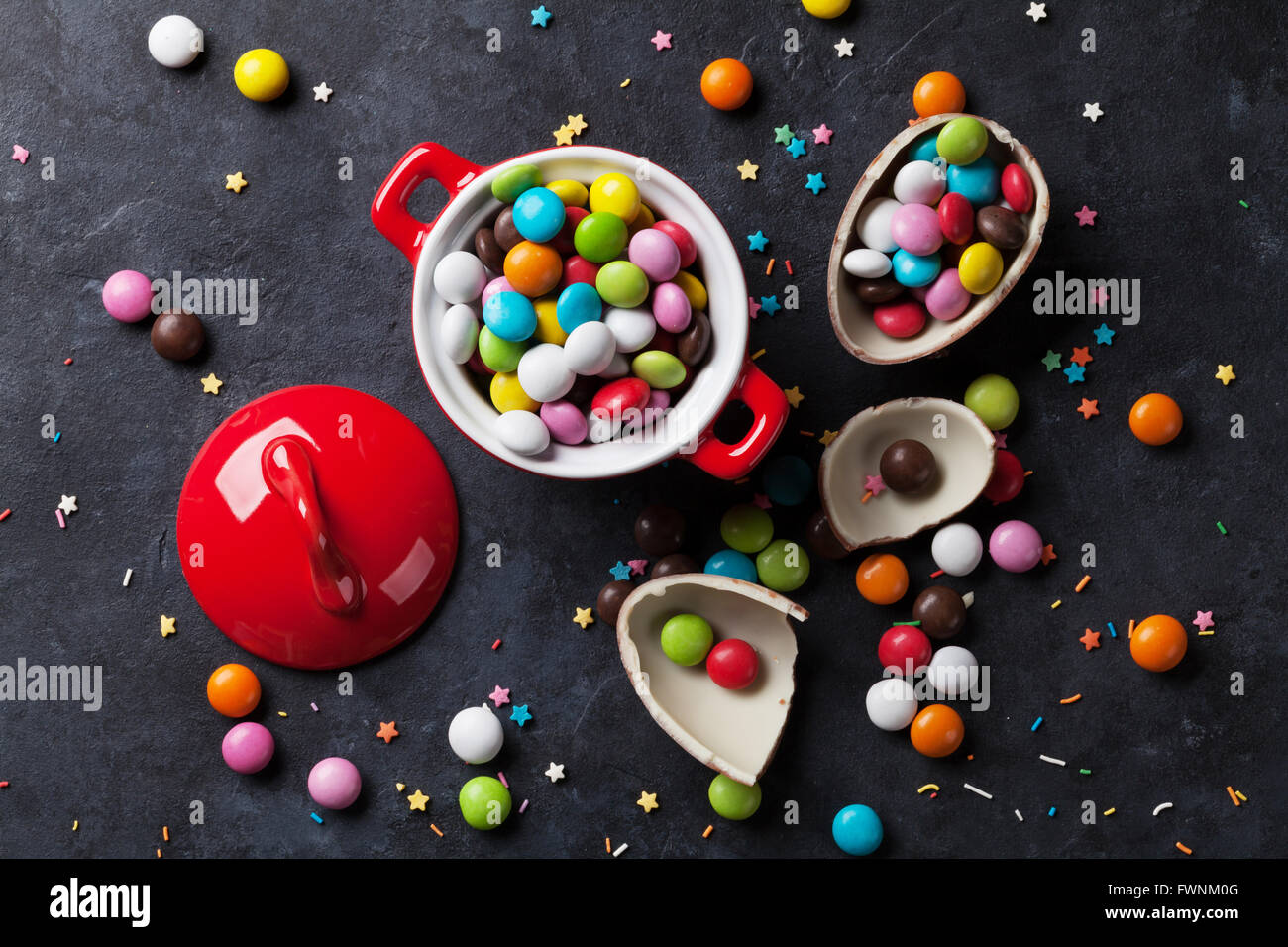 Caramelos de colores y huevo de chocolate sobre fondo de piedra. Vista superior Foto de stock