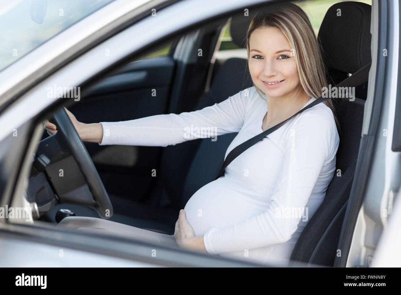La mujer embarazada en el coche usando el cinturón de seguridad, vista  lateral Fotografía de stock - Alamy