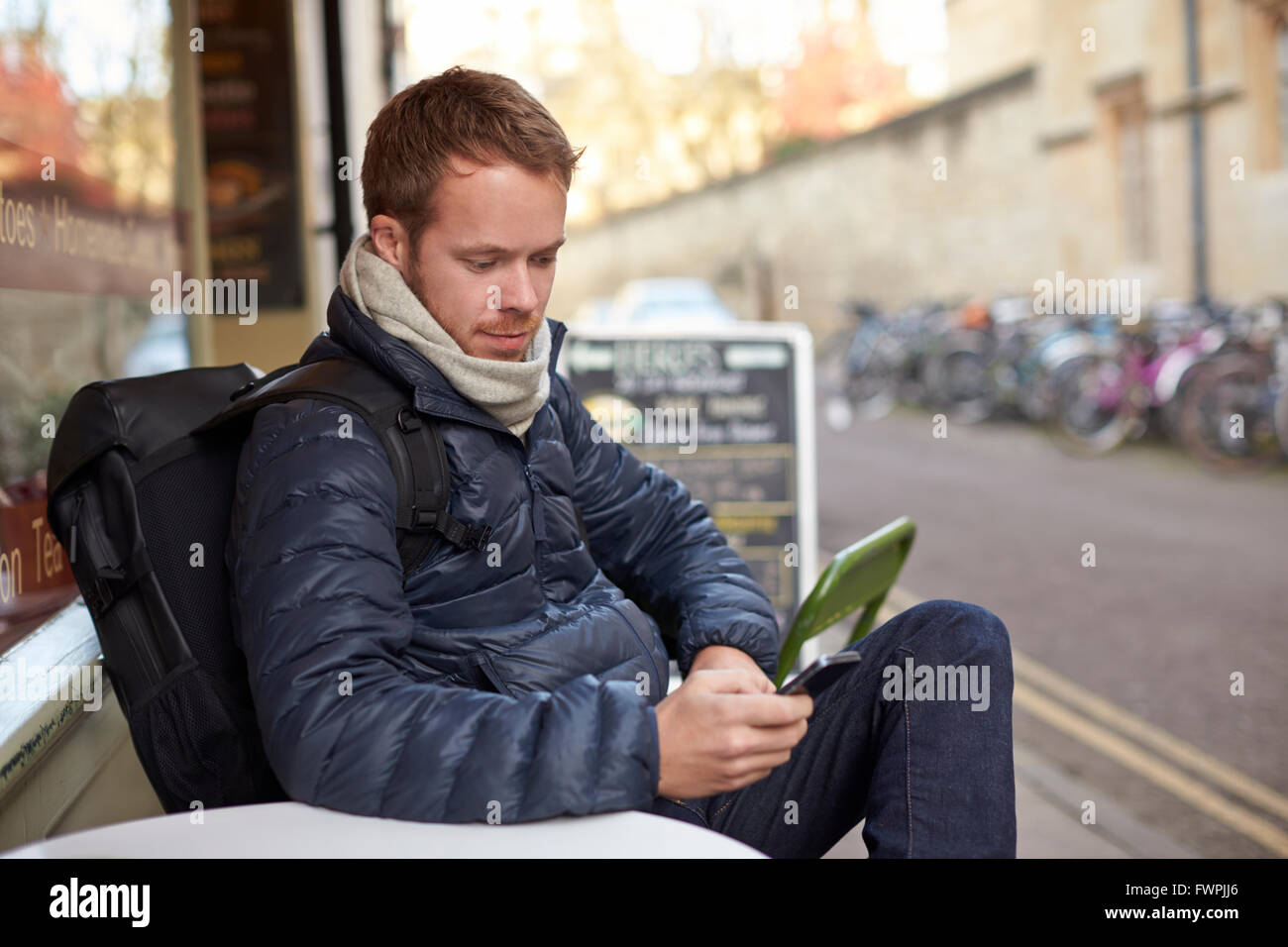 Hombre sentado fuera de Cafe Enviar mensaje de texto Foto de stock