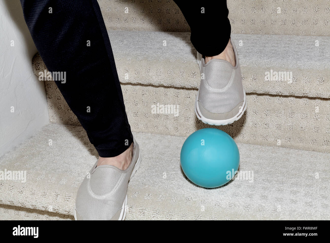 Los pies de una mujer bajando las escaleras con una bola en la forma provocando un accidente Foto de stock