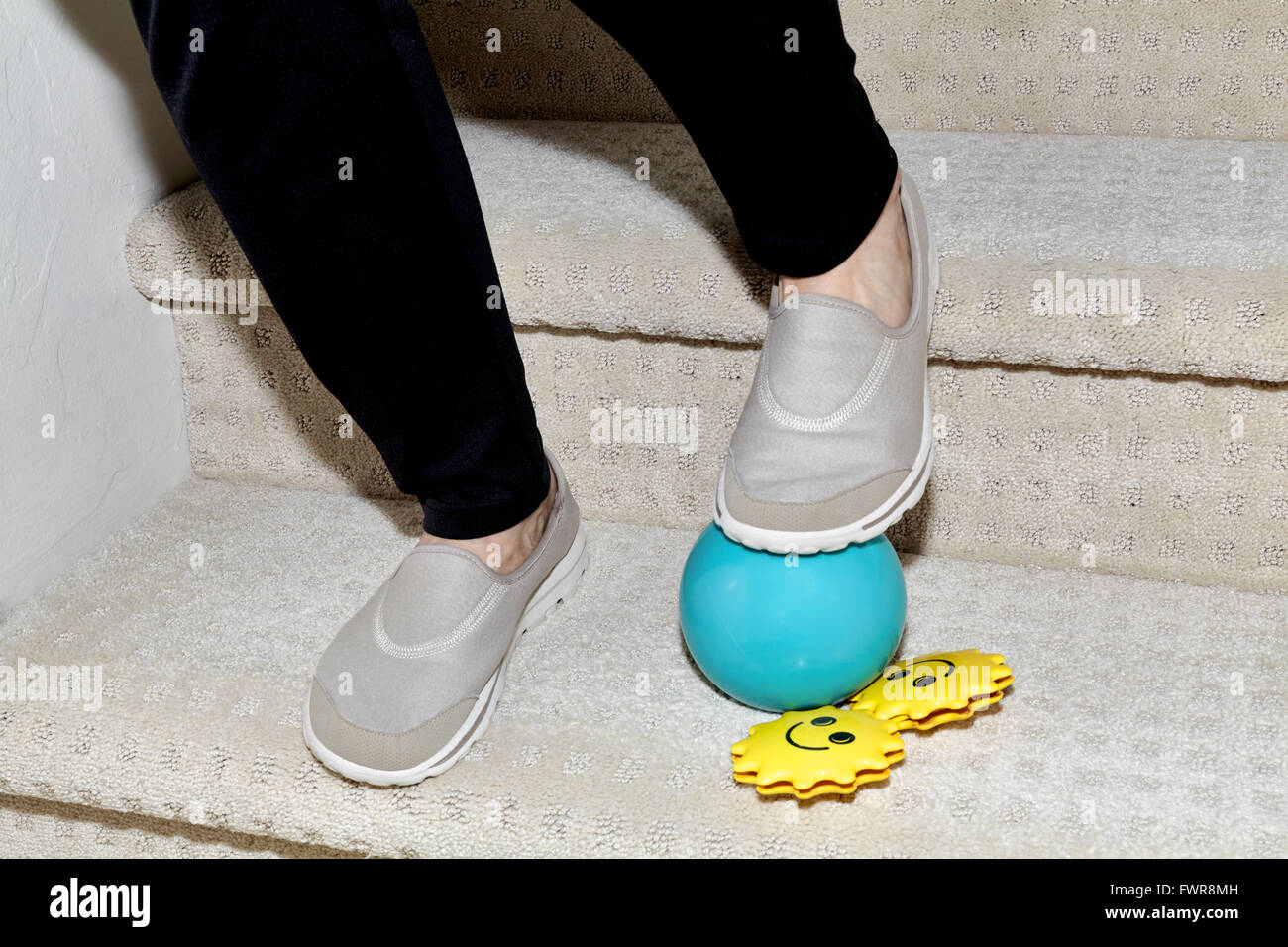Los pies de una mujer bajando las escaleras con una pelota y un juguete childs en la manera de causar un accidente Foto de stock
