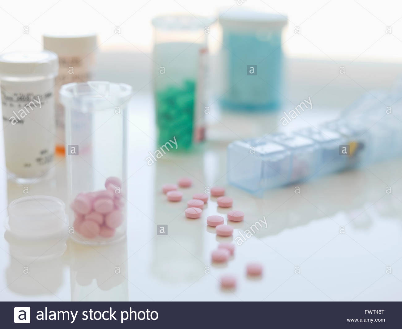 Las botellas de las píldoras y tabletas en la tabla contra el fondo blanco. Foto de stock