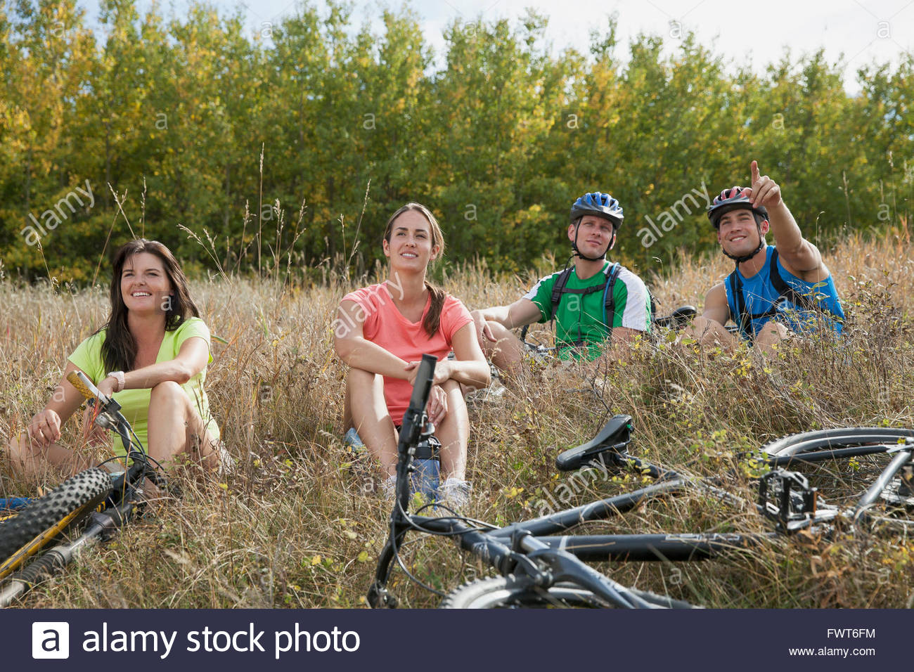 Cuatro personas relajante en el campo con las bicis. Foto de stock