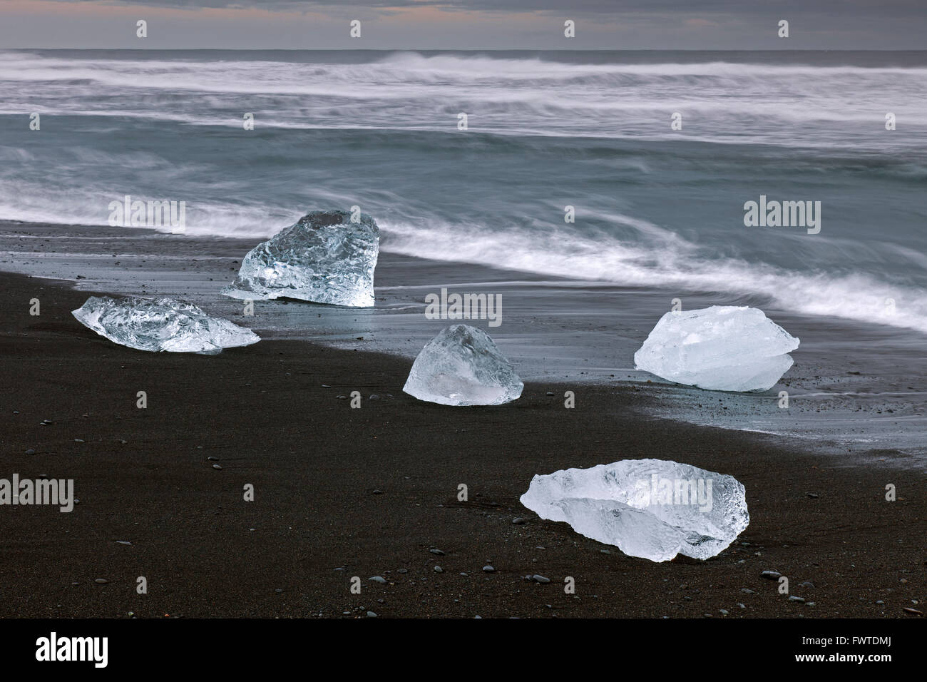Derretimiento de bloques de hielo que se lava en la playa a lo largo de la costa del Océano Atlántico en Breidamerkursandur arenas negras en invierno, Islandia Foto de stock