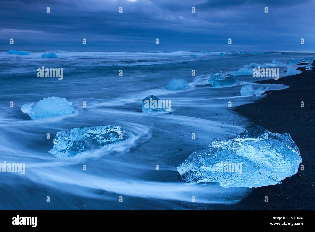 Derretimiento de bloques de hielo que se lava en la playa a lo largo de la costa del Océano Atlántico en Breidamerkursandur arenas negras en invierno, Islandia Foto de stock