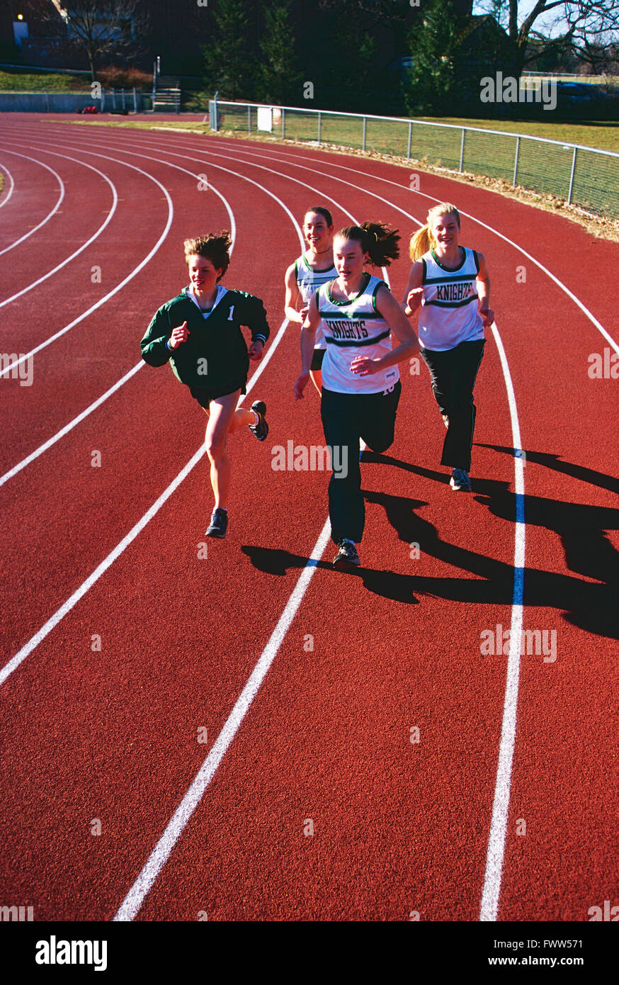 Niñas de escuela secundaria vía equipo corriendo en pista al aire libre de superficie sintética Foto de stock