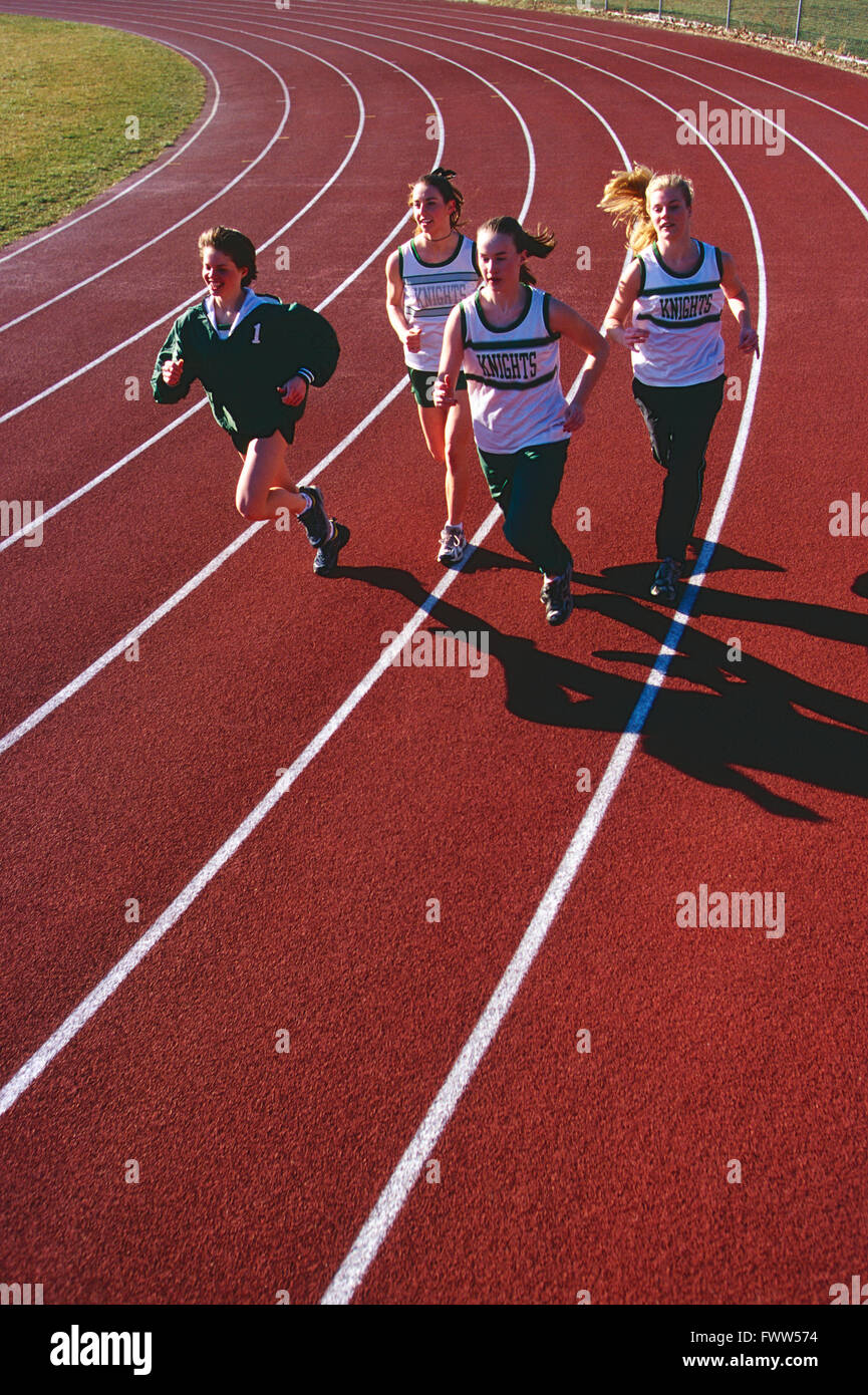Niñas de escuela secundaria vía equipo corriendo en pista al aire libre de superficie sintética Foto de stock