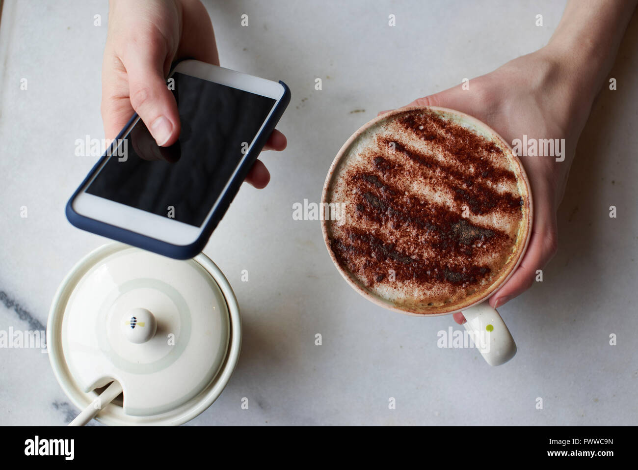 Mujer enviar mensaje de texto y beber cappuccino Foto de stock