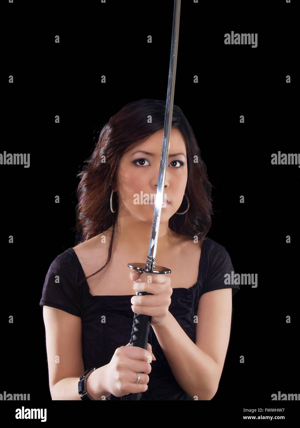 Joven Mujer Asiática sosteniendo la espada japonesa delante de la cara Foto de stock