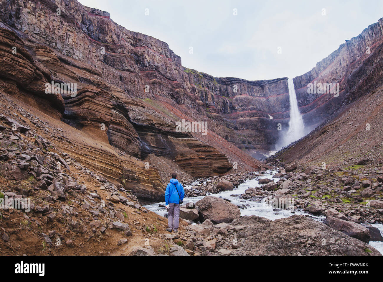 Caminante caminando hasta Hengifoss cascada en Islandia, hermoso paisaje increíbles Foto de stock