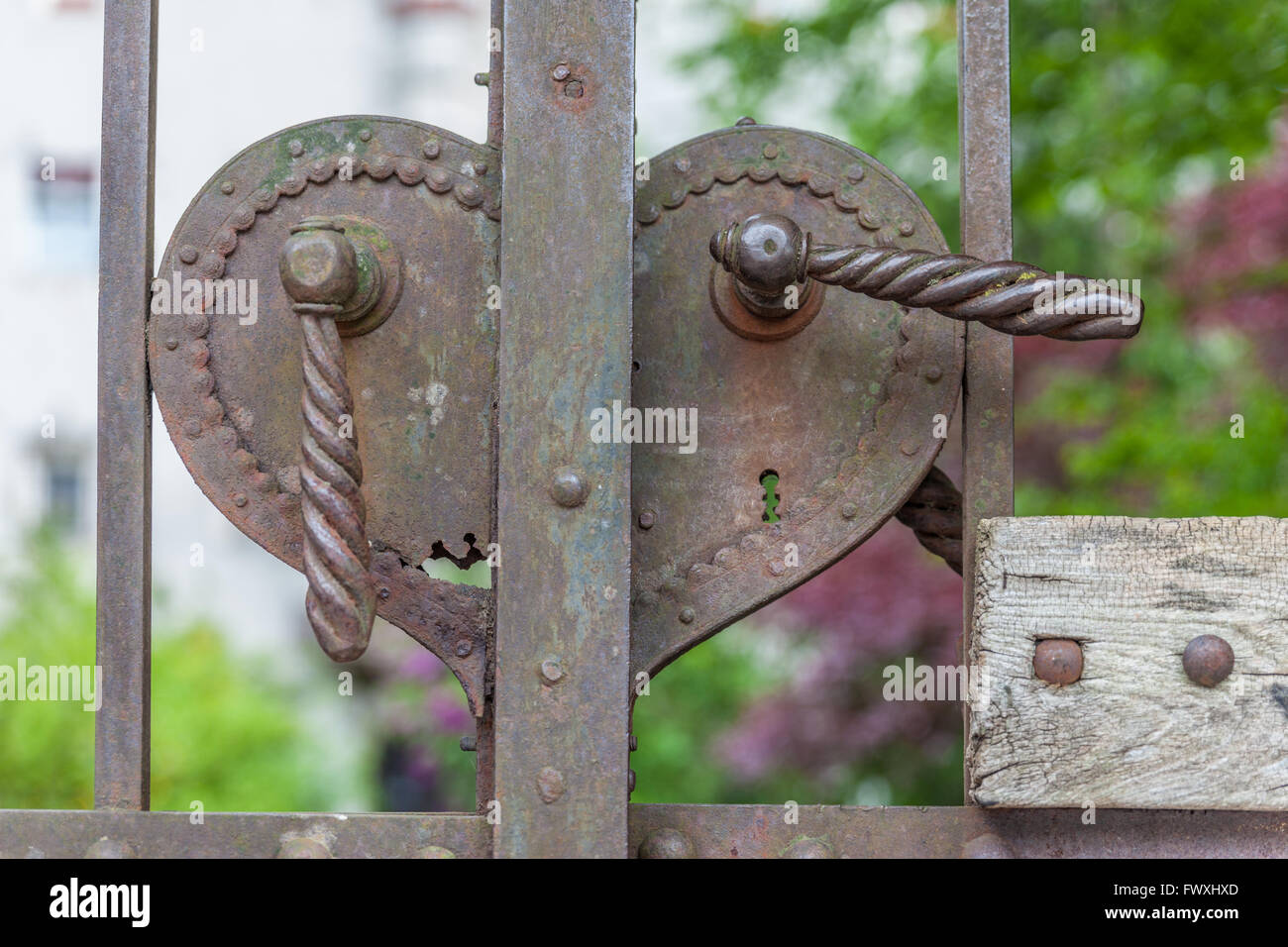 Old rusty la manija de la puerta en forma de corazón en un gran portal de hierro Foto de stock