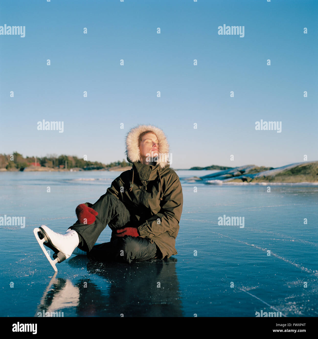 Suecia, Uppland Varmdo, Bjorno, mitad mujer adulta sentada en lago congelado Foto de stock
