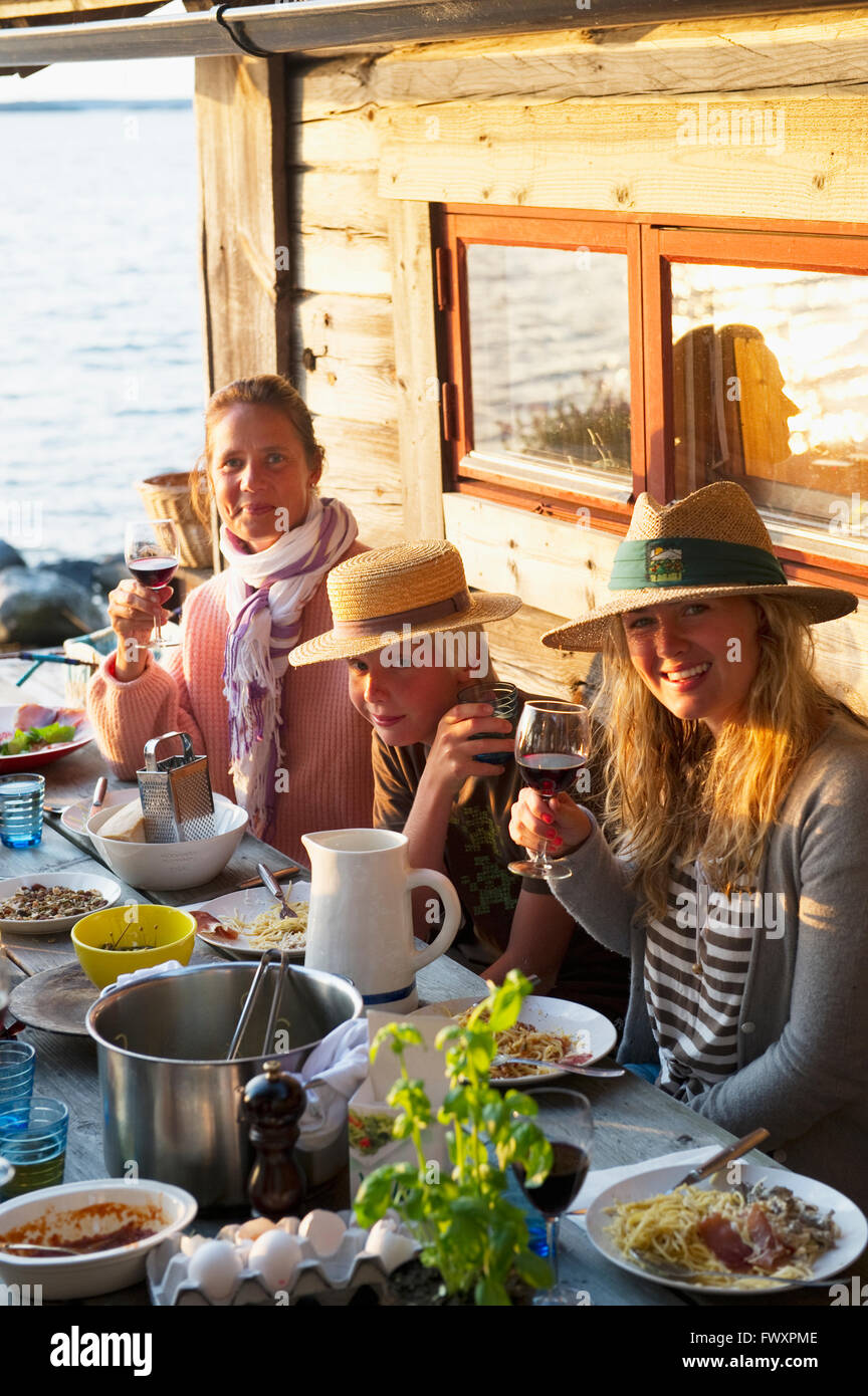 Suecia, Estocolmo, dos mujeres maduras y adolescente (16-17) sentados en la mesa Foto de stock