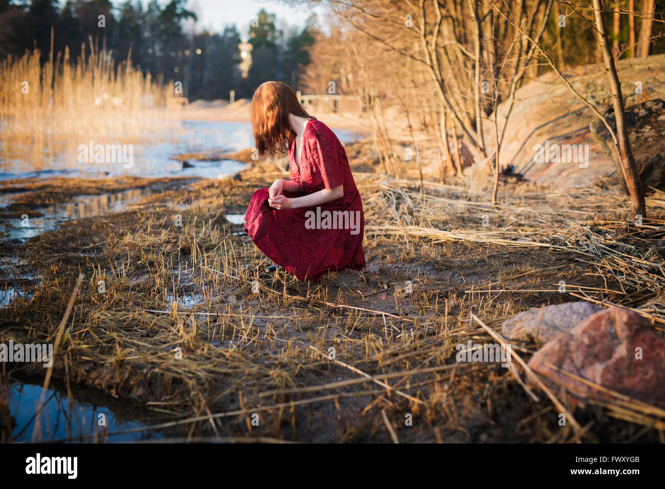 Finlandia, Varsinais-Suomi, joven mujer agazapadas en los humedales Foto de stock