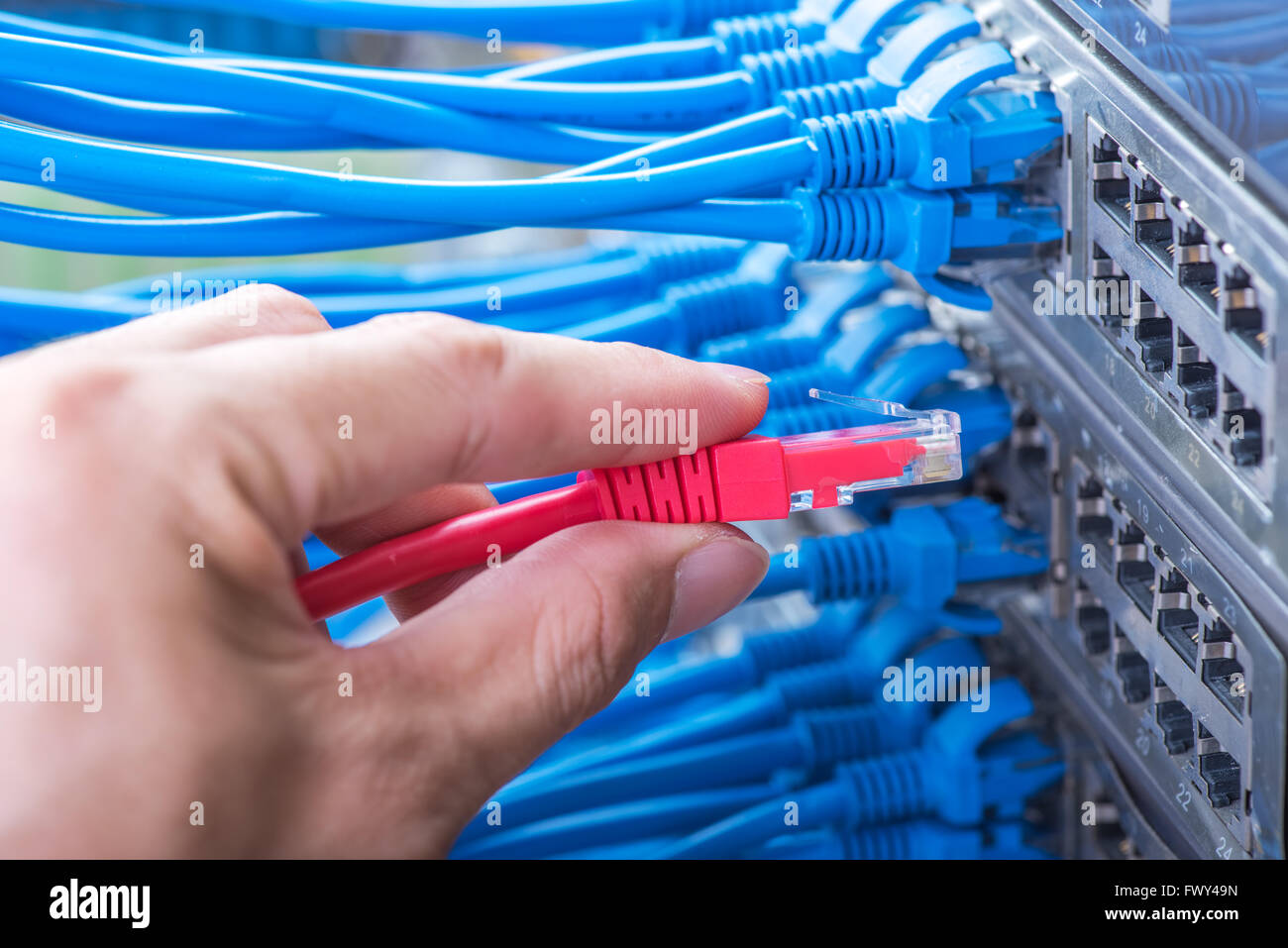 Hombre trabajando en la sala de servidores de red con cubo de fibra óptica para las comunicaciones digitales e internet Foto de stock