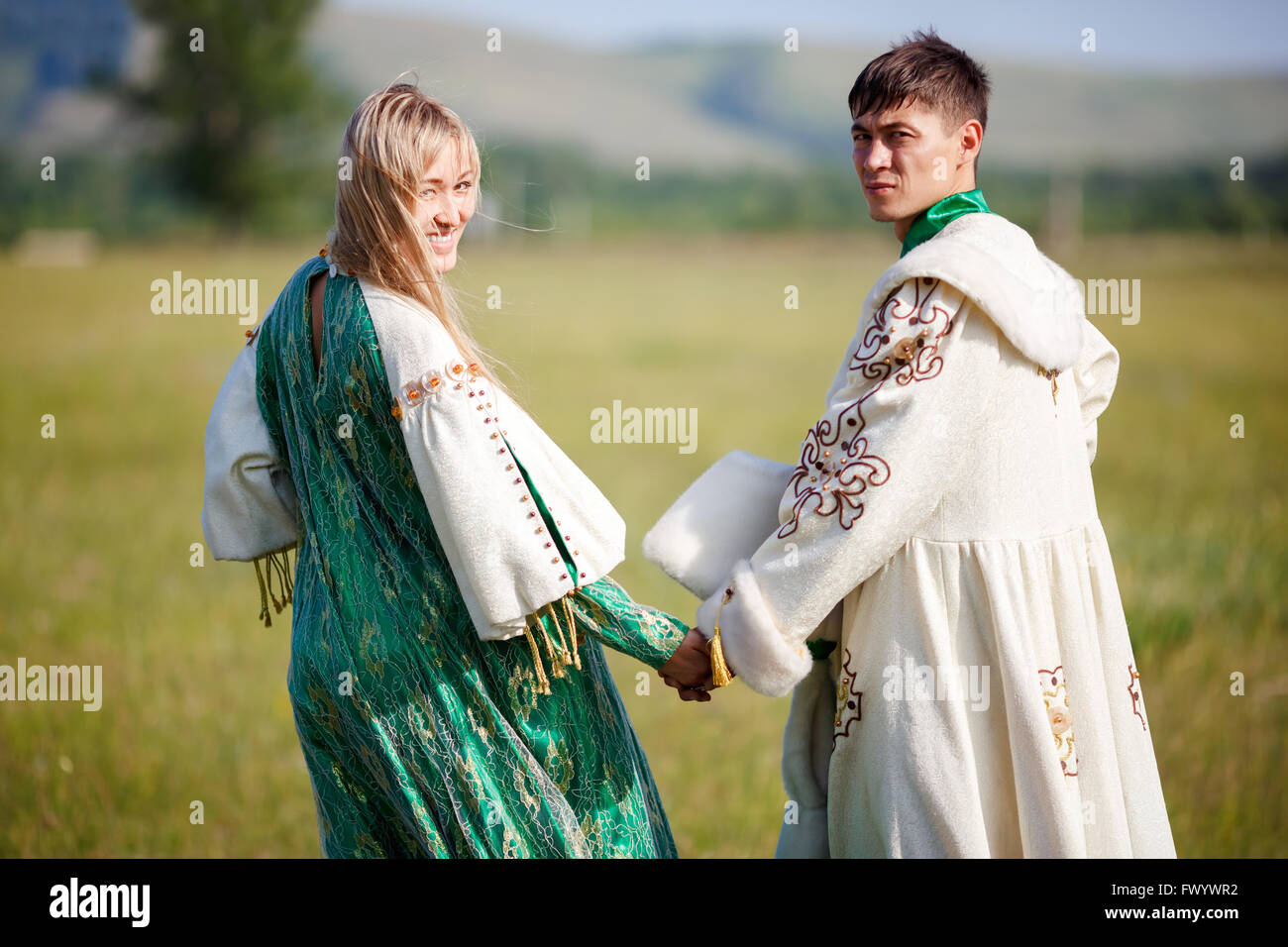 Par de trajes étnicos, tomarse de las manos, volvió a la cámara. Foto de stock