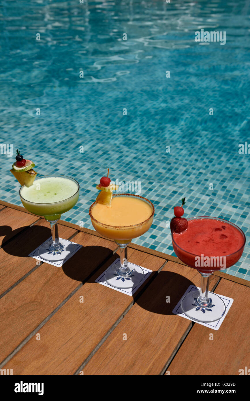 Rojo amarillo y verde cócteles en un deck de madera junto a una piscina Foto de stock