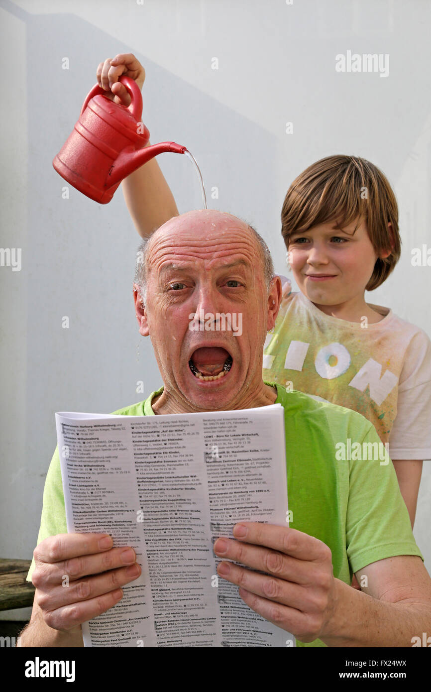 Naughty boy verter agua sobre la cabeza de un hombre Foto de stock