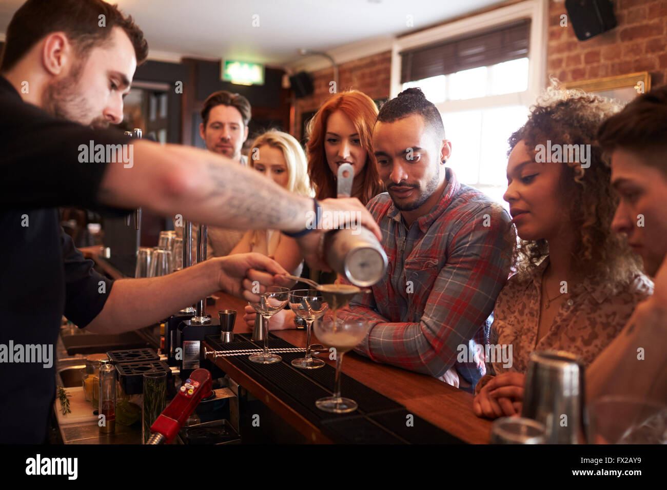 Cantinero dando lecciones de preparación de cócteles a los amigos en el bar Foto de stock