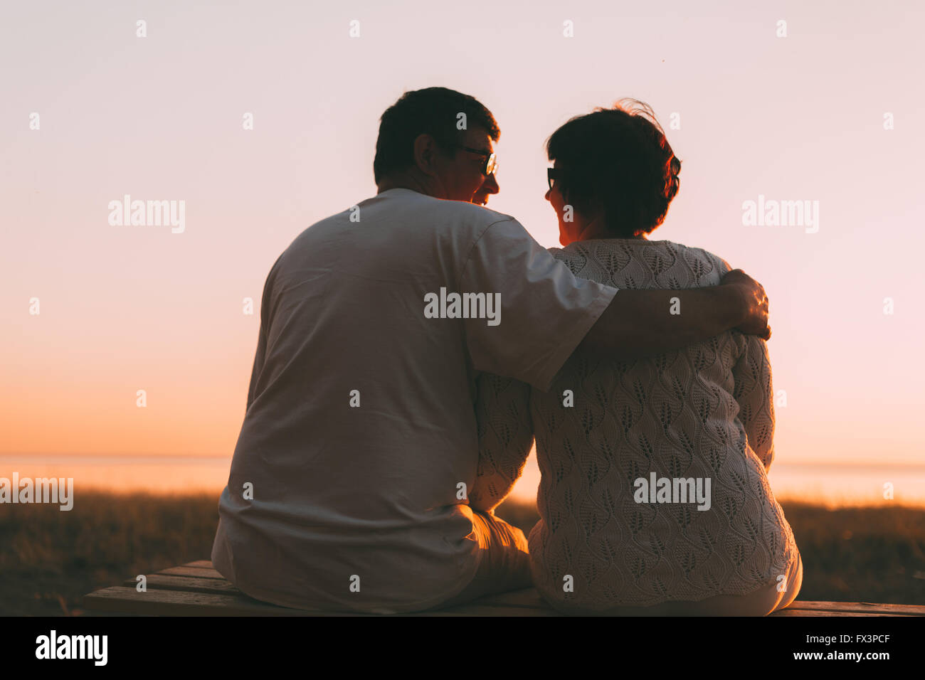 Pareja adulta abrazando a la puesta del sol y el mar. Foto de stock