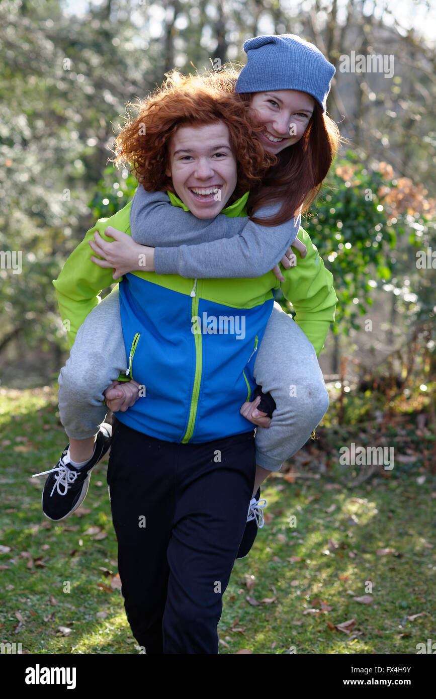 Joven llevando a su hermana en su espalda, piggyback, hermanos pelirroja, Baviera, Alemania Foto de stock