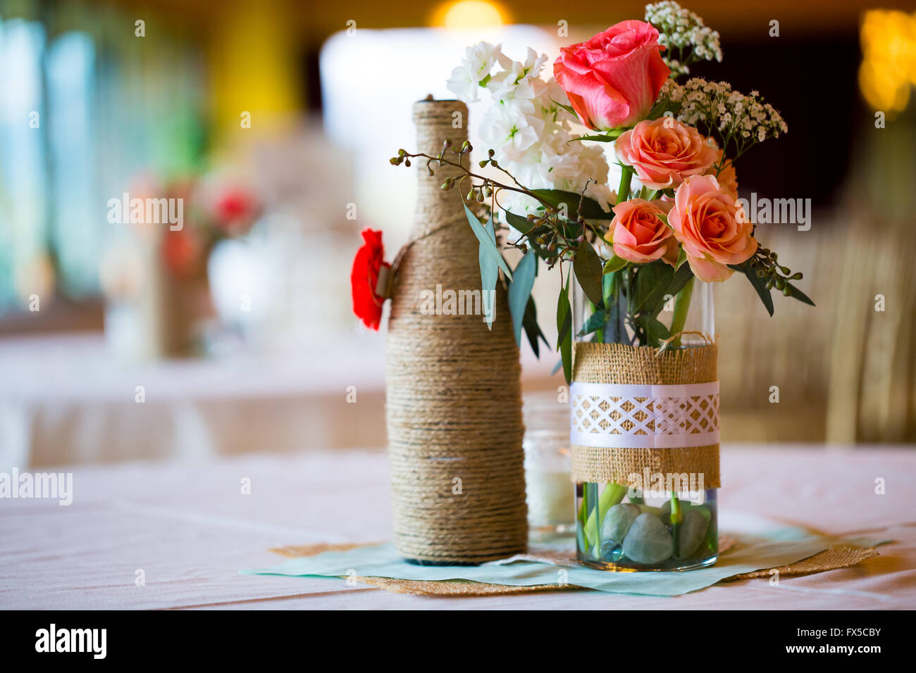 Boda de bricolaje Tabla decoración centros de mesa con botellas de vino  envuelta en arpillera hilo y rosas flores Fotografía de stock - Alamy