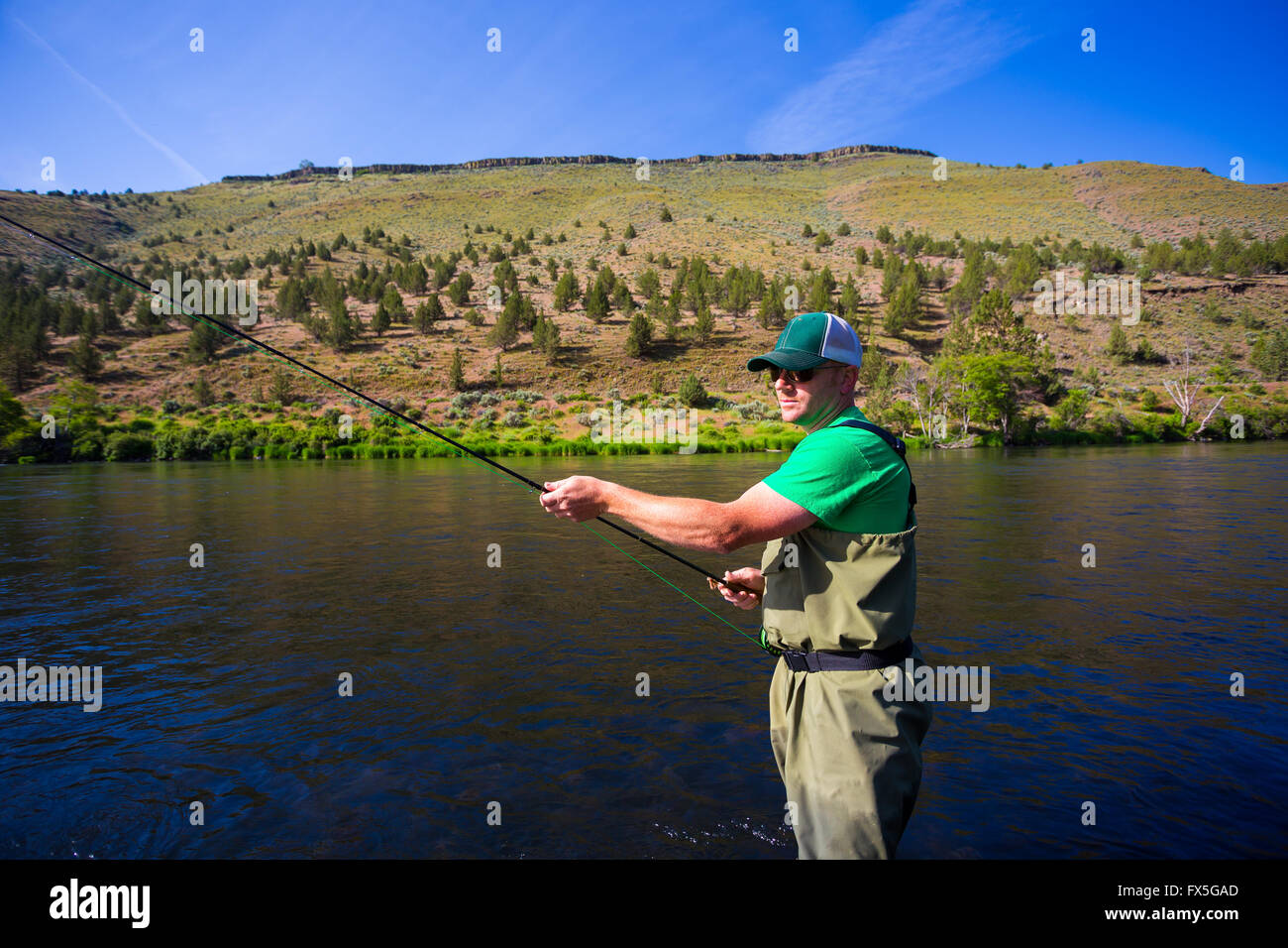 Experimentado pescador con mosca de pesca en el río de Deschutes Oregon, casting para pescar mientras está de pie en el agua. Foto de stock