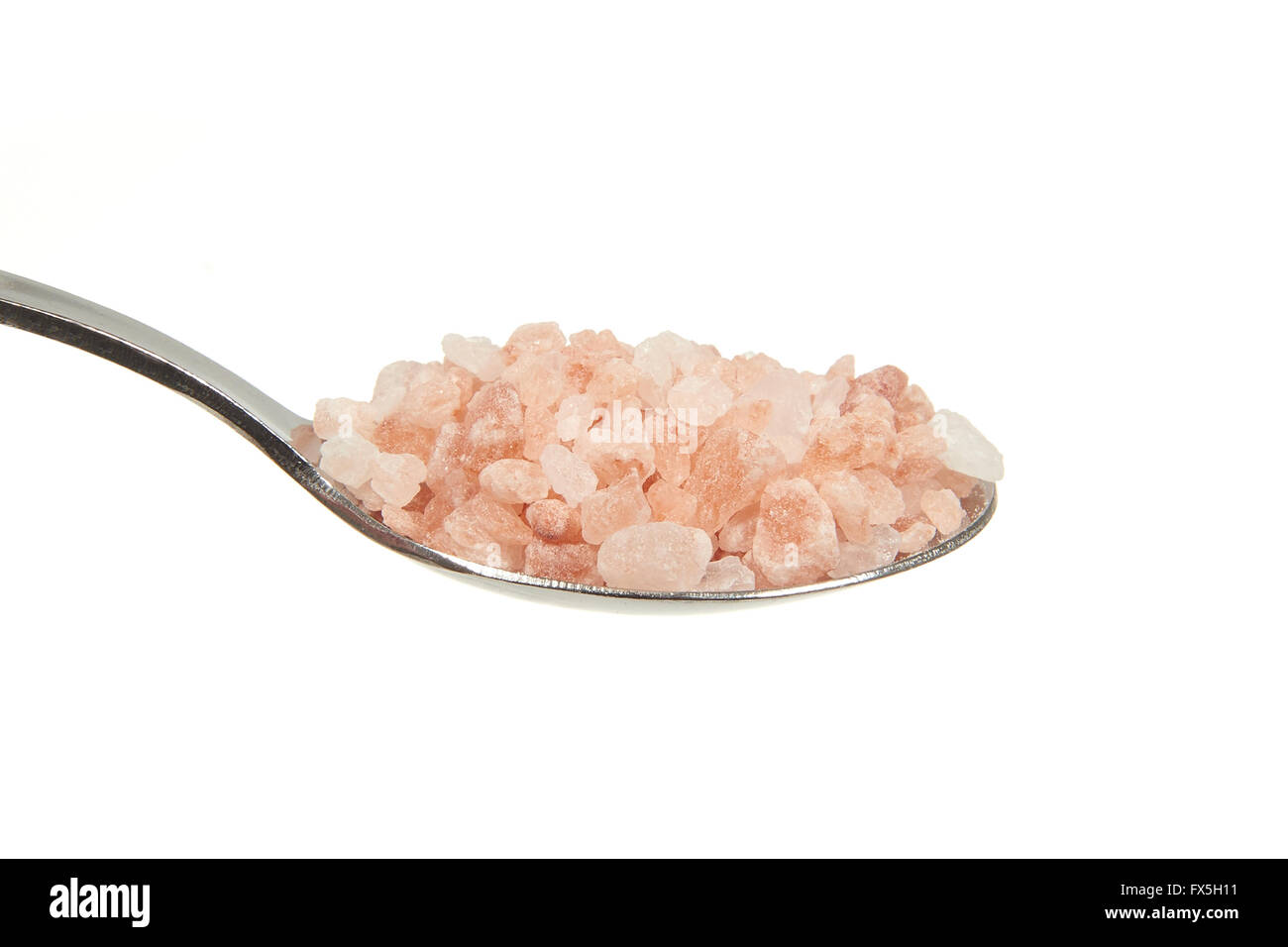 Rosa Himalayan Salt sobre una cucharadita sobre un fondo blanco. Foto de stock