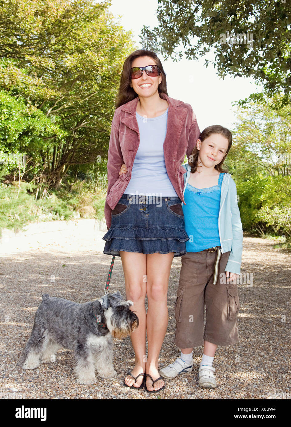 Madre e hija caucásica paseando a un perro en la ruta Foto de stock