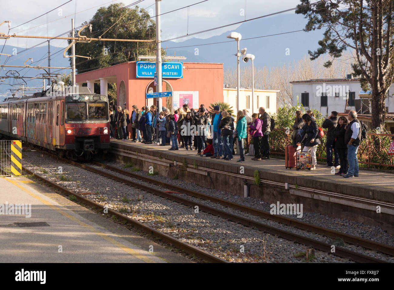 Pasajeros que esperan el tren de Sorrento a Nápoles en la línea Circumvesuviana en la estación de tren de Pompeya - Pompeya Scavi-Villa dei Misteri, Italia Foto de stock
