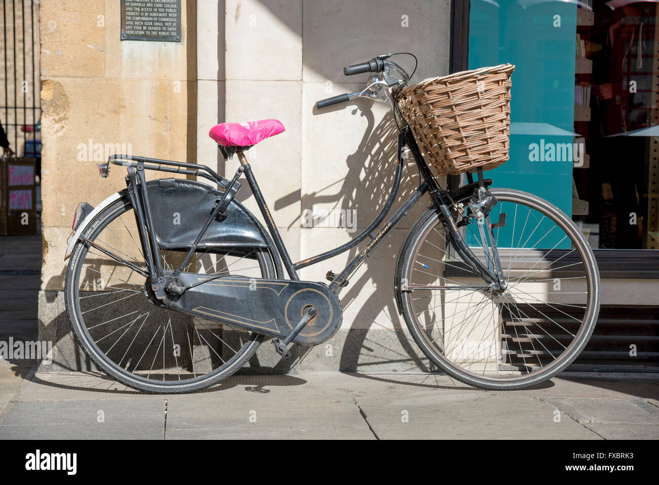 Una bicicleta tradicional estacionado contra una pared en sunshine en Cambridge, Reino Unido Foto de stock