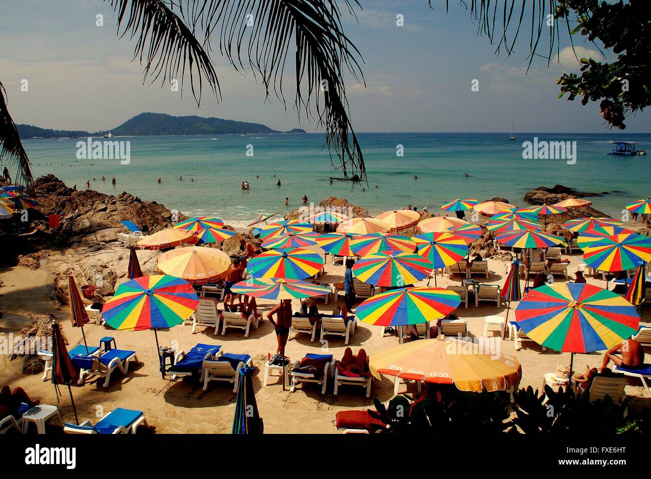 Phuket, Tailandia: coloridas sombrillas sombra bañistas sentados en sillas alquiladas en la arena de la playa de Patong Foto de stock