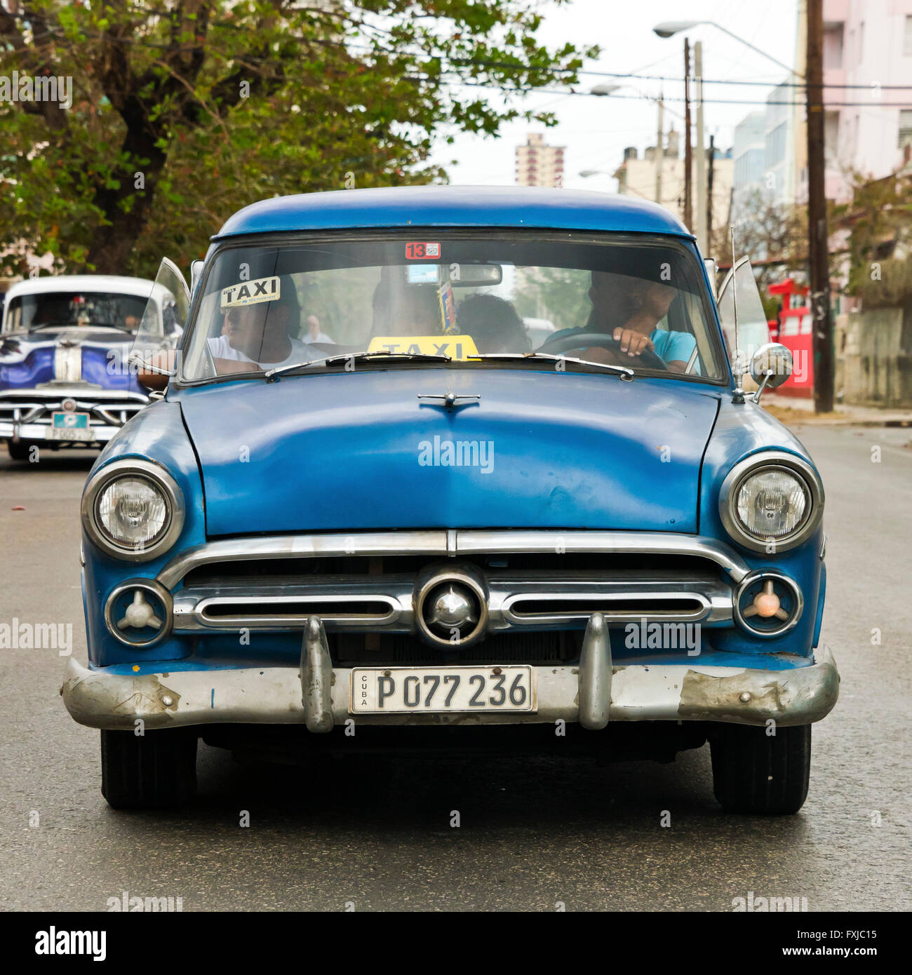 Plaza cerca de un antiguo clásico coche americano a lo largo de la carretera en La Habana, Cuba. Foto de stock