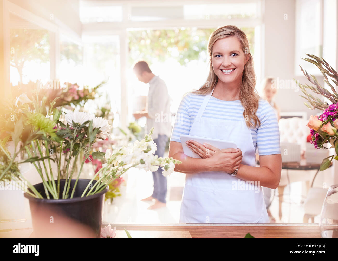 Retrato sonriente floristería con digital comprimido en flower shop Foto de stock