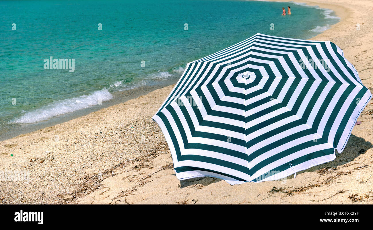 La sombrilla de rayas en una playa, en Córcega, en el mar azul turquesa Foto de stock