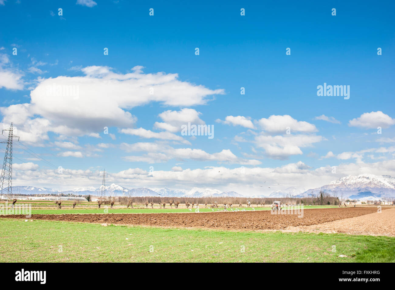 El paisaje agrícola. Con el tractor en un campo arado. Las montañas en el fondo. Foto de stock