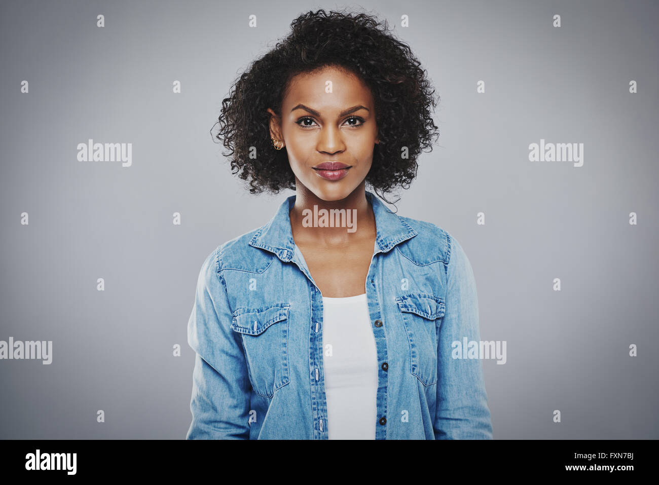 Grave mujer hermosa negro con camisa de Jean azul sobre fondo gris  Fotografía de stock - Alamy