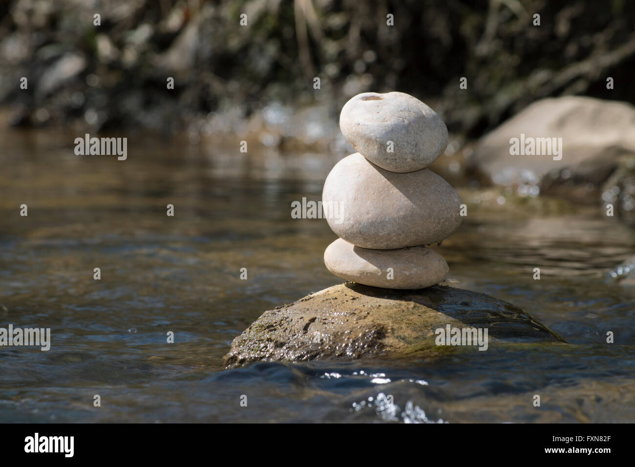Piedras de meditación sentada en Boulder por stream Foto de stock