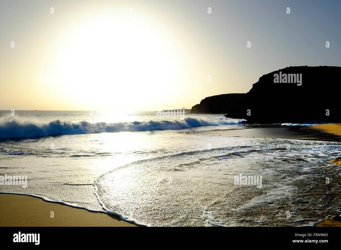 Las olas rompen en la orilla como el sol sobre la playa de Papagayo, Lanzarote Foto de stock