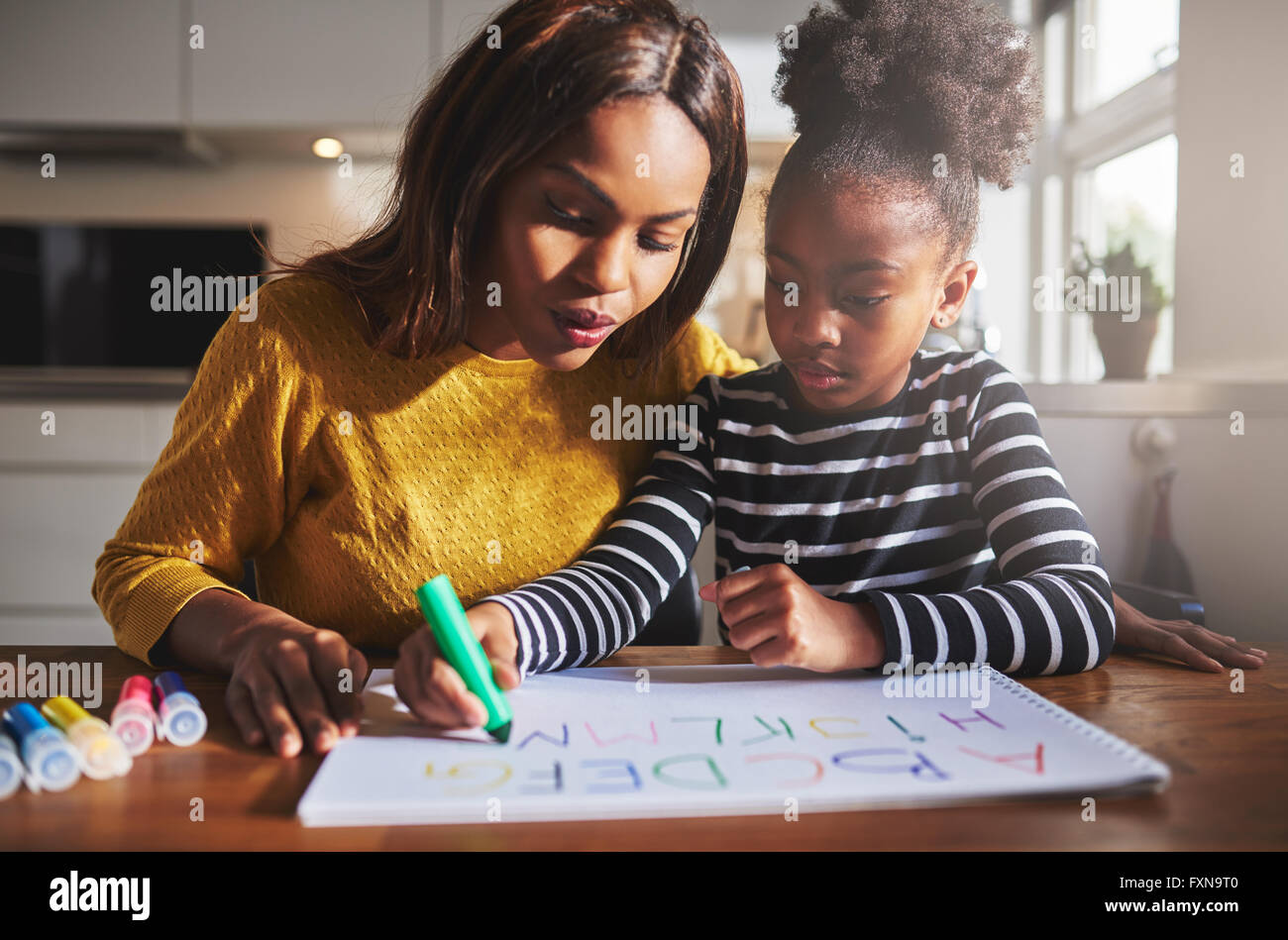 La madre y el niño negro haciendo los deberes, aprender el alfabeto Foto de stock