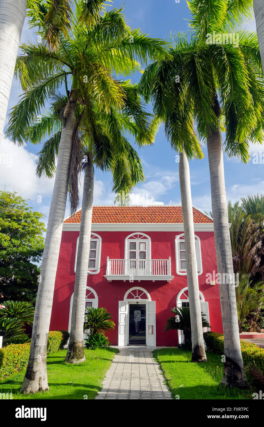 Rojo edificio de estilo colonial holandés con altas palm treesbeside la acera, Willemstad, Curacao Foto de stock