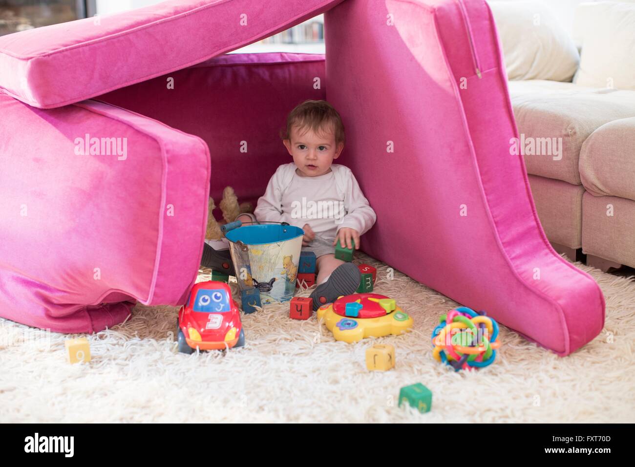 Baby Boy jugando en fort realizados desde el sofá cojines Foto de stock